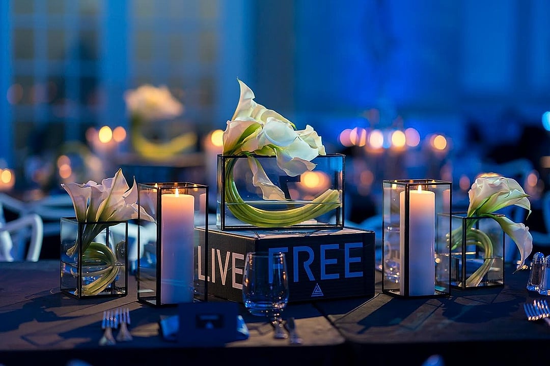 Calla lily centerpieces and pillar candles on a dark table in blue light