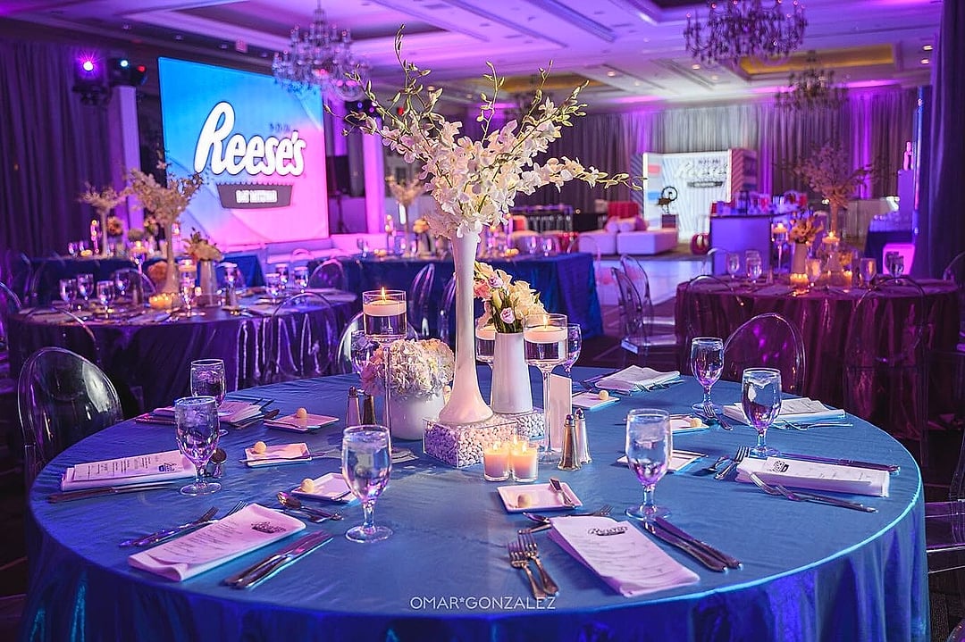 Round table in blue linen with tall floral centerpiece and screen beyond