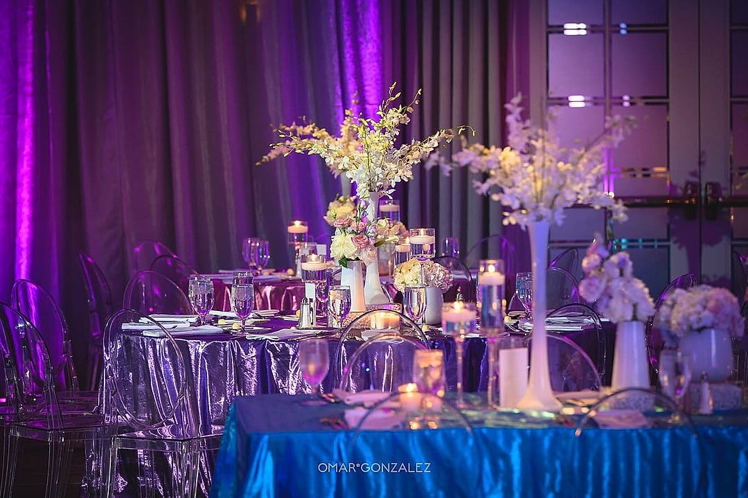 Tables with tall white floral arrangements in purple and blue light