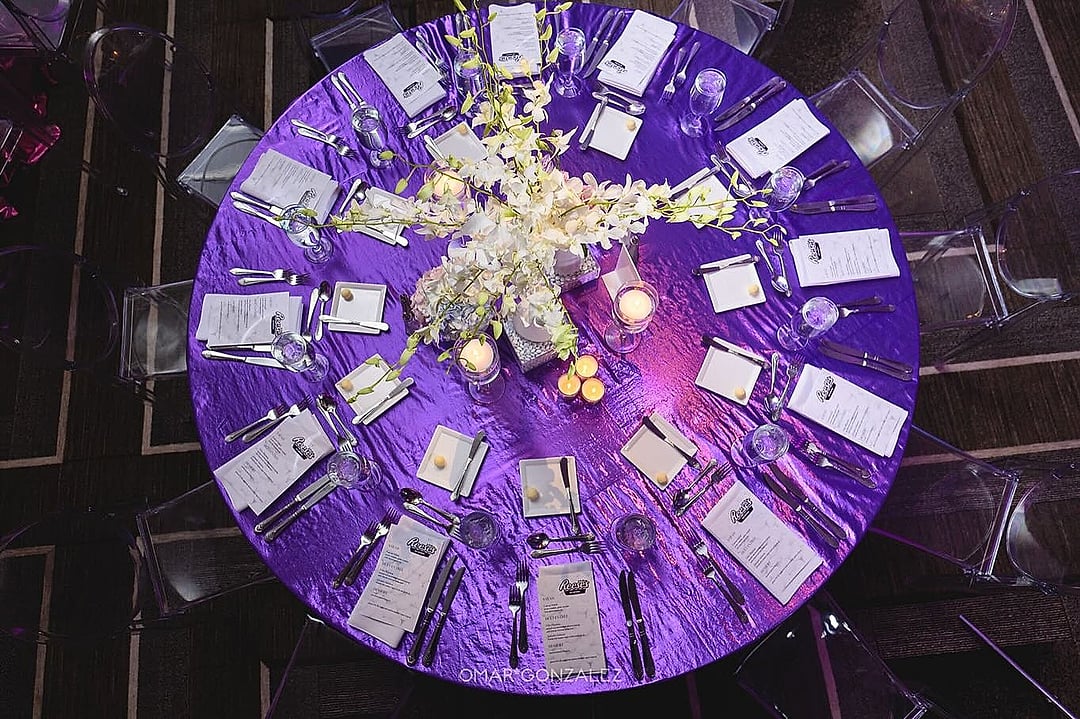 Overhead view of a round table set in purple linen with white orchids