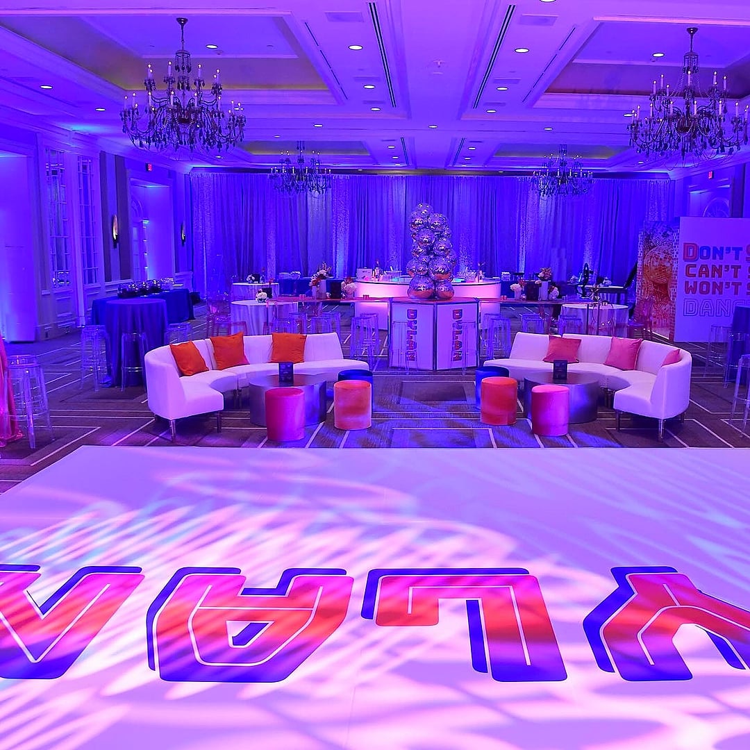 Purple ballroom with white lounge seating and a custom dance floor