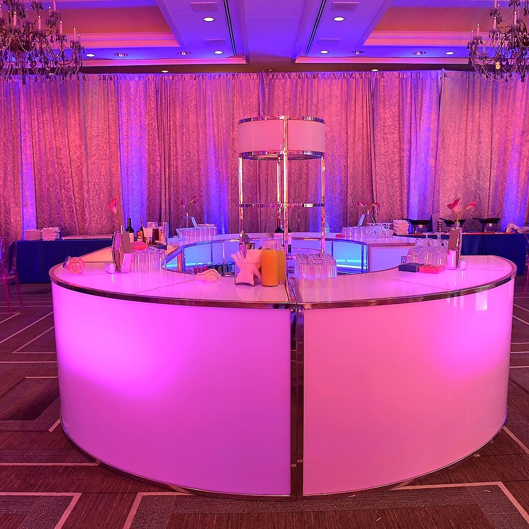 Round illuminated pink bar beneath chandeliers