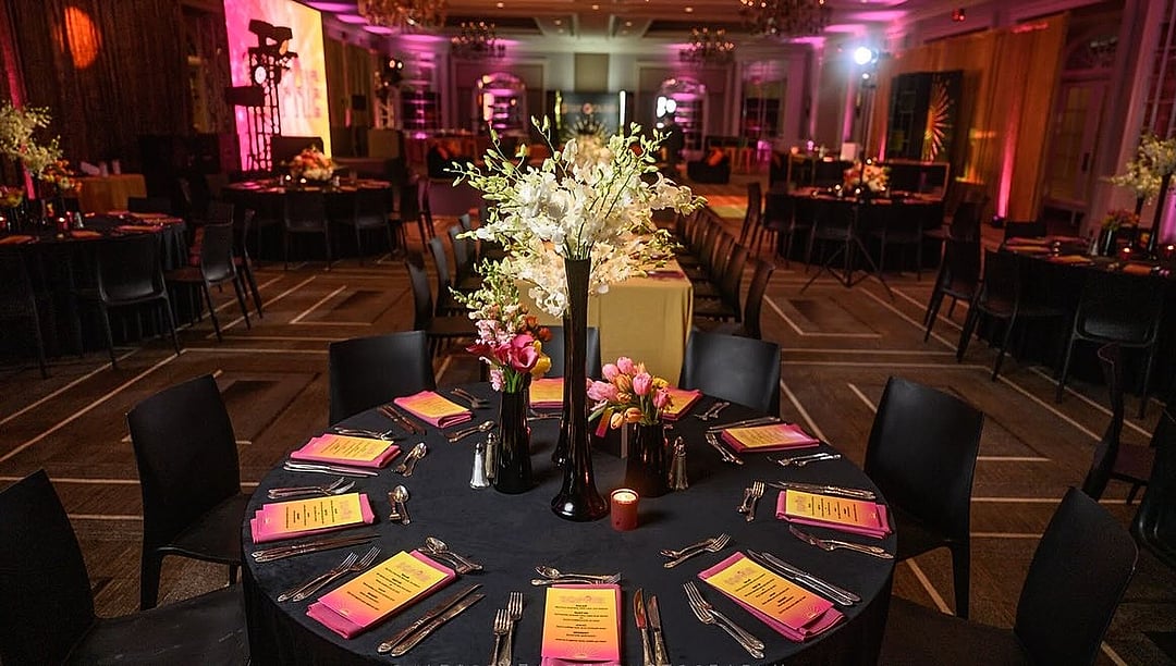 Dining room of black-linen tables with bright floral centerpieces