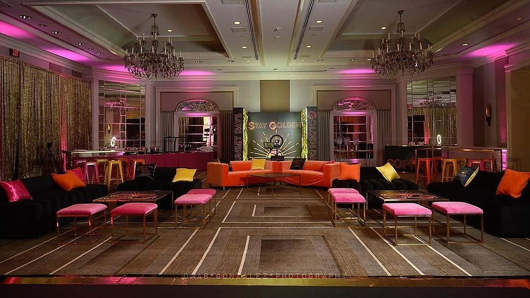 Ballroom lounge with orange and pink seating beneath chandeliers