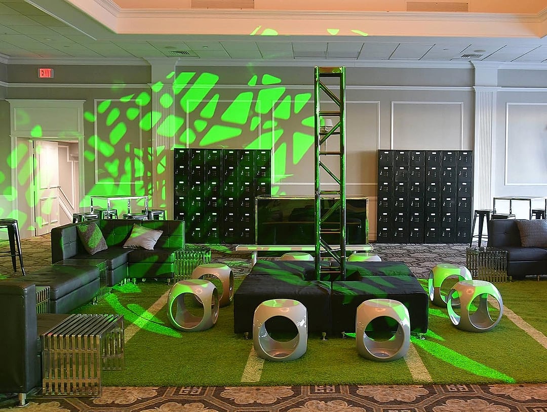 Lounge with locker walls, green gobo lighting and a truss tower