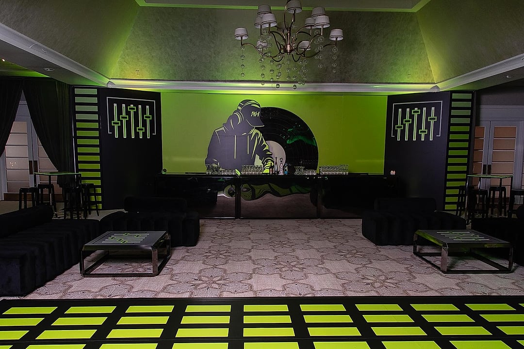 Lounge seating facing a DJ backdrop over a patterned dance floor